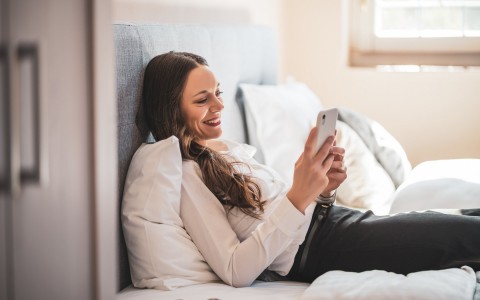 woman looking at phone while smiling