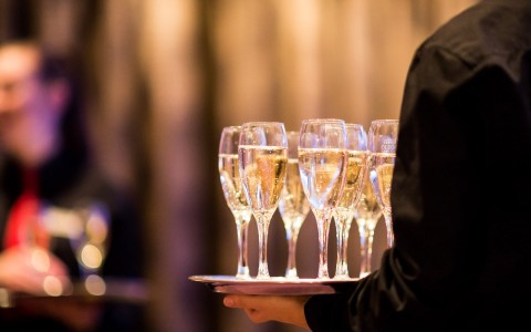 server holding plate with champagne flutes
