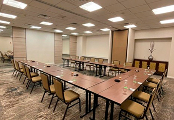 Bolero meeting room with a U shaped brown table and brown chairs, bright lights and enough space for multiple people