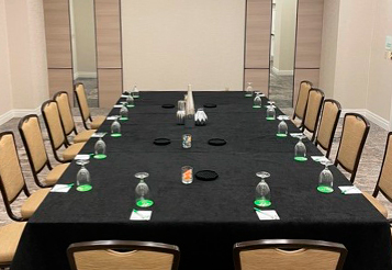 Rumba meeting room with a long rectangular table with a black tablecloth. light beige chairs lined up all the way around the table 
