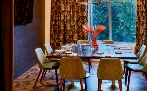 large dining table in front of a large window and large curtains zoomed in