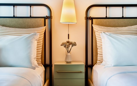 partial view of two hotel beds and lamp between them