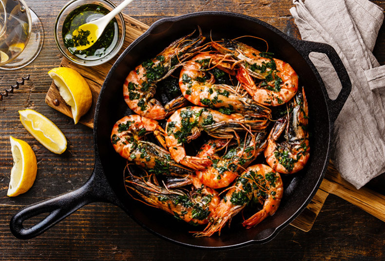 shrimp garnished with herbs in a cast iron skillet