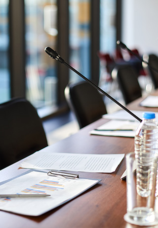 close up of a conference table with documents on the table and microphones at each chair