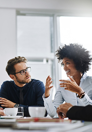 man and woman sitting at a conference table having a discussion with coffee