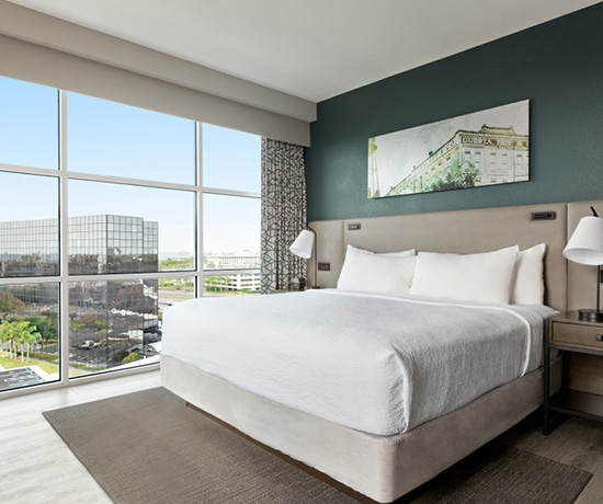 queen bed with white linens and a large window