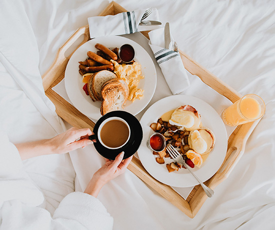 a breakfast in bed with eggs and fruit and coffee