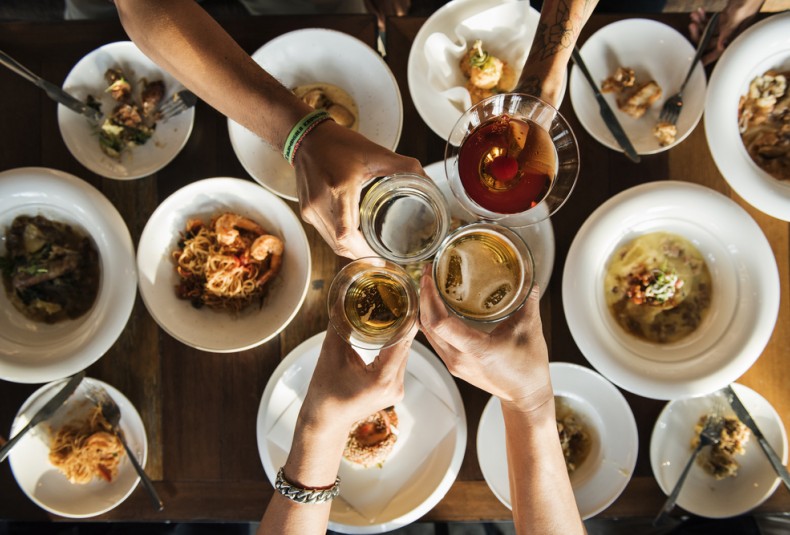 group of friends cheersing over a table of food