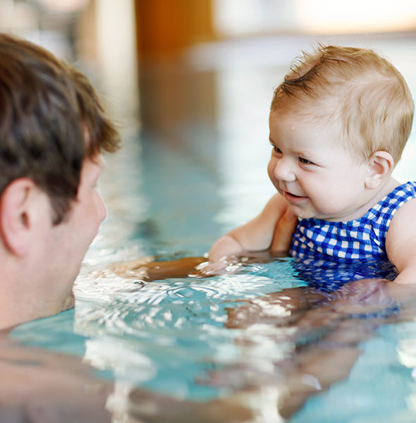 a dad swimming in the pool with a baby