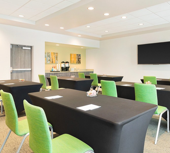 a meeting room with black tables and green chairs