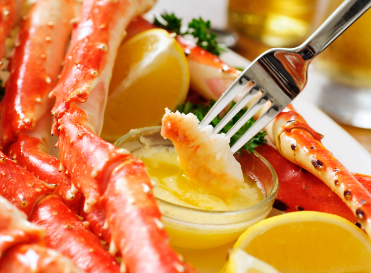closeup of cooked crab being dipped in a butter sauce