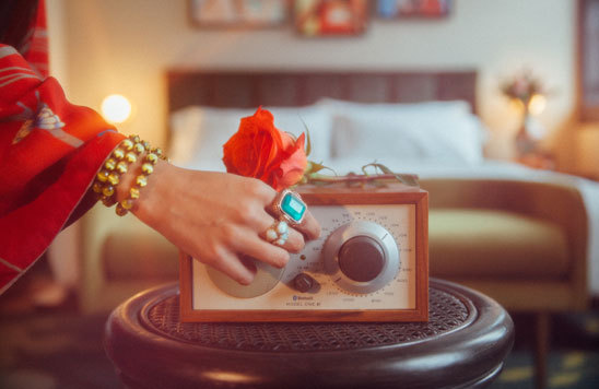 Female hand turning on a radio infront of a hotel bed