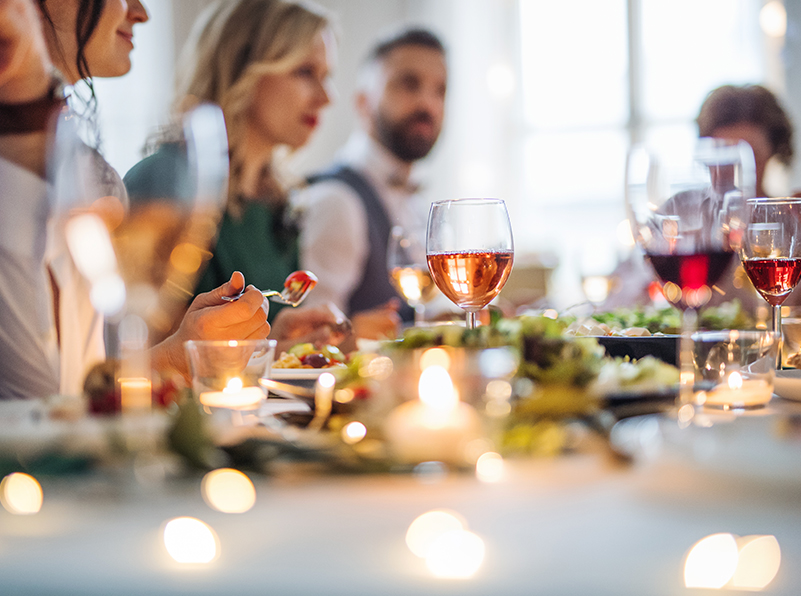 People gathered in the table, having some food and glass of wine