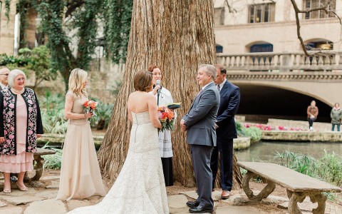 people getting married under a large tree outside