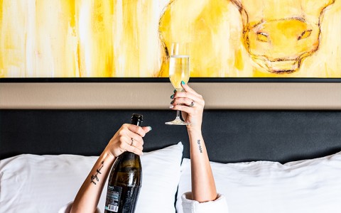 a woman laying in bed holding up a bottle of champagne 