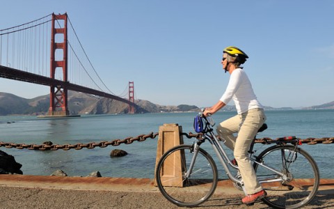 man riding a bike with the golden gate bridge in the back 