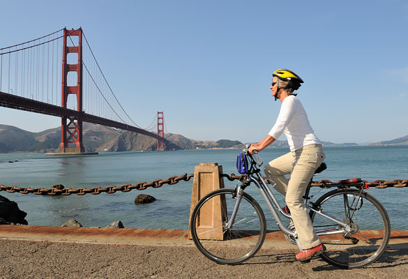 man riding a bike with the golden gate bridge in the back