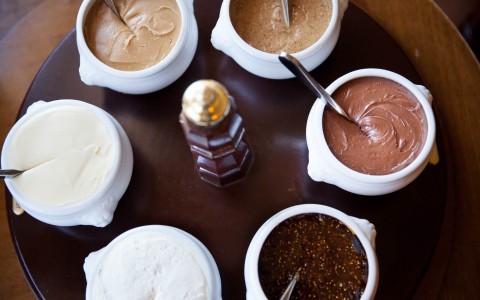 six small bowls of condiments on a round table