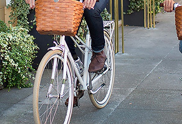 man riding white bike with brown weaved basket on front