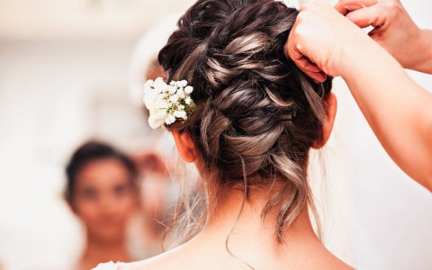 A bride and her updo with small white flowers in her hair next to her ear.