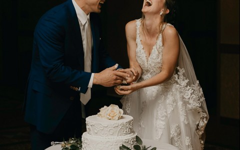 A smiling bride and groom with their wedding cake.