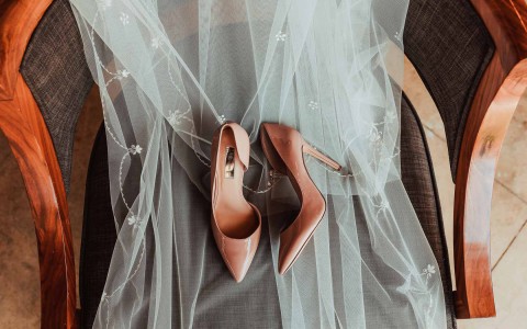 a view of a pair of heels laid out over a bride's veil