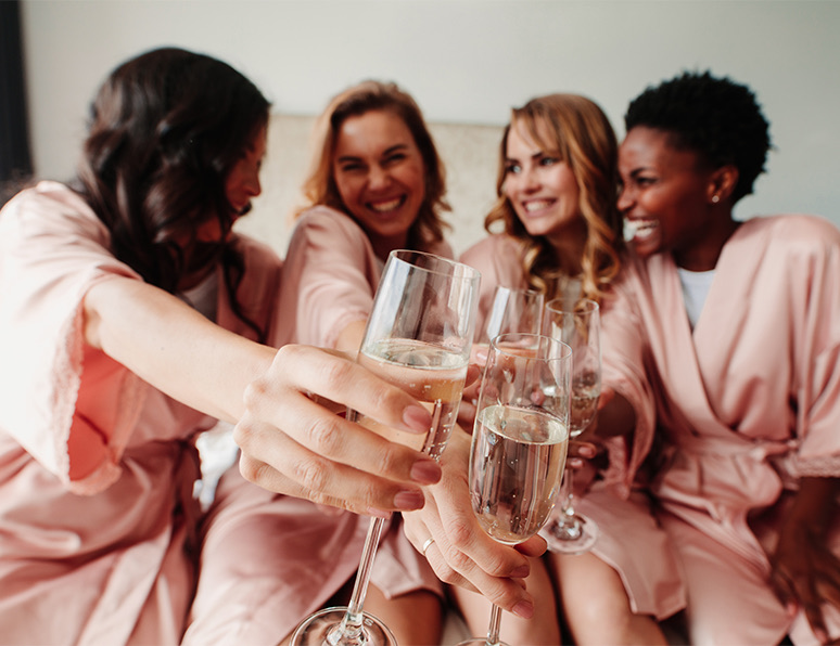Four women in a room smiling and holding champagne glasses.