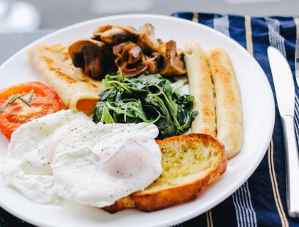 a plate with bread, eggs, greens and tomatoes