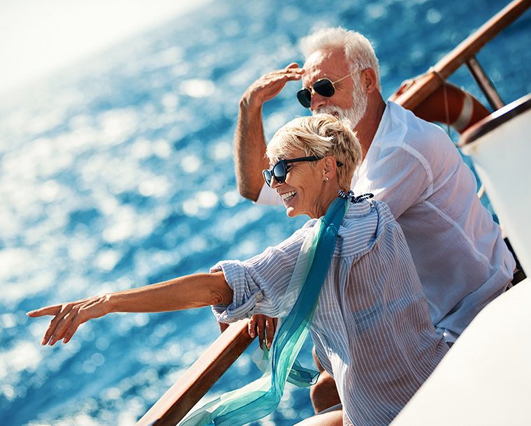 An elderly couple on a boat in the water pointing to something in the distance