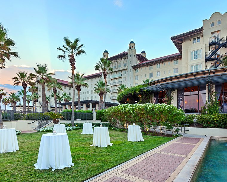 Cocktail tables covered in white tablecloths on an outdoor lawn outside the hotel