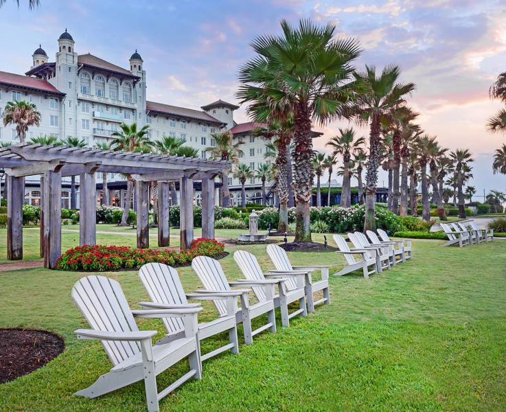 Outdoor lawn chairs sitting on well kept grass with the hotel in the background
