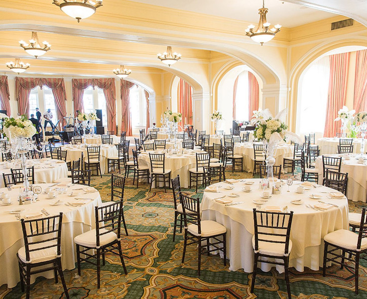 An event space decorated for a dinner reception with many circular tables and a band setting up in the back