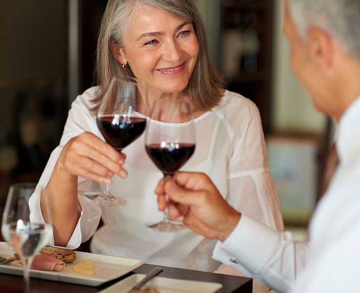 senior couple toasting glasses of red wine at a table