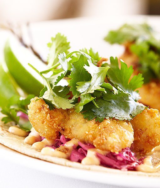 Close up of a fried meat taco garnished with herbs