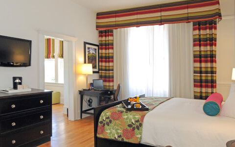 hotel room with desk, dresser, and colorful decorations