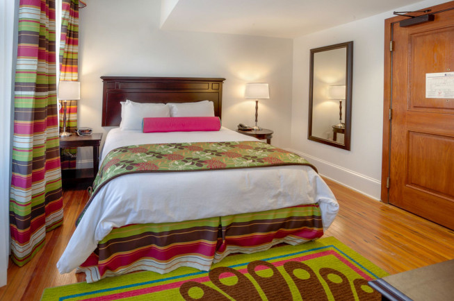 queen bed with colorful blanket and pink pillows