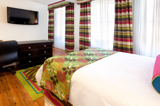 hotel suite with dresser tv and colorful curtains