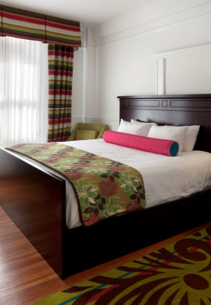 King bed with green blankets and pink pillows