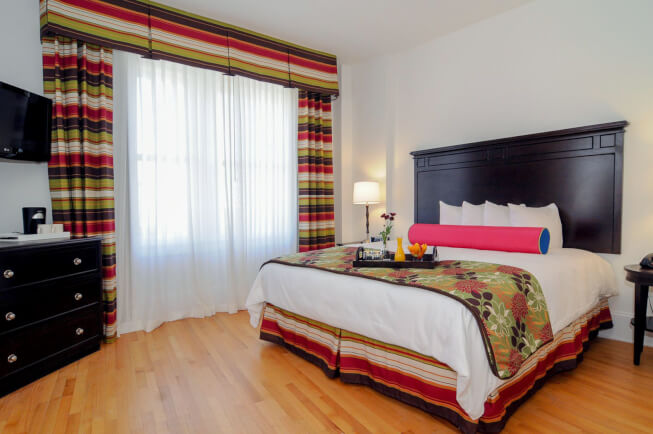 King bed with wood bed frame and colorful curtains