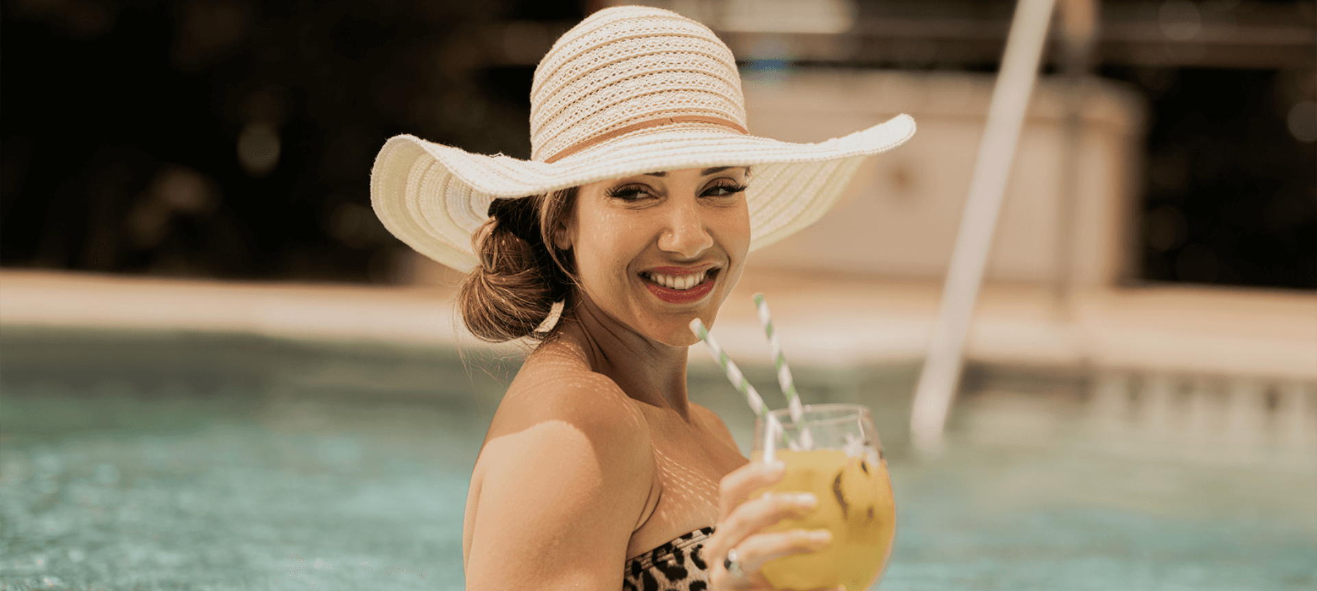 woman in pool with cocktail in hand
