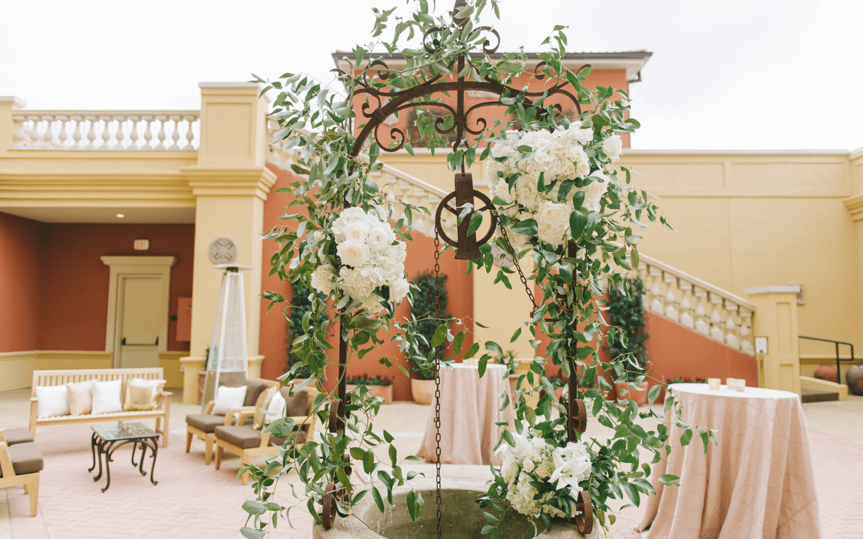 florals draped over outdoor well in courtyard for wedding reception