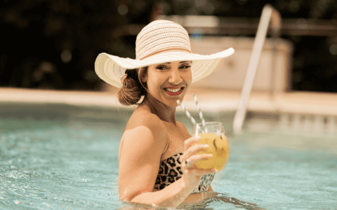 Female wearing sunhat and holding refreshing beverage in pool