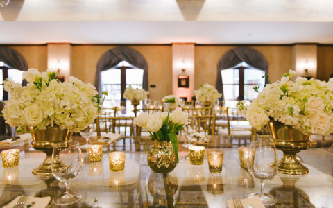 votive candles and white floral arrangements on table during wedding reception