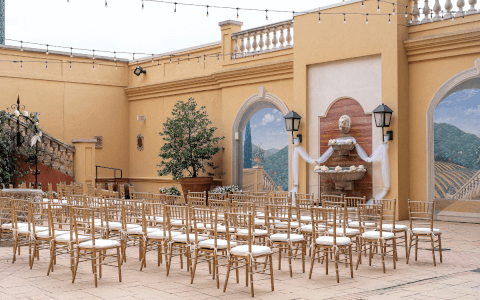 gold chiavari chairs lined up for wedding ceremony in outdoor courtyard