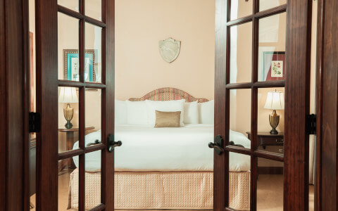 view of the king bed through the beautiful dark brown, wooden doors