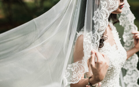 up-close view of the brides wedding dress and the details on her vail