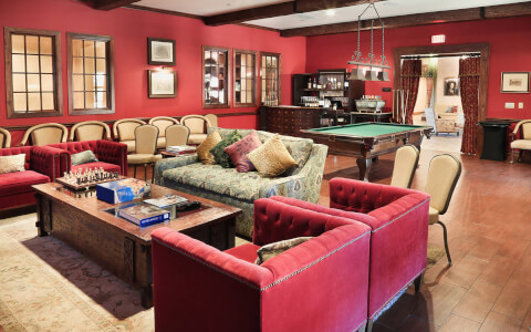 red sofa chairs in a red room that has a pool table in the back
