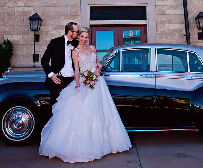 bride and groom posing near a classic car