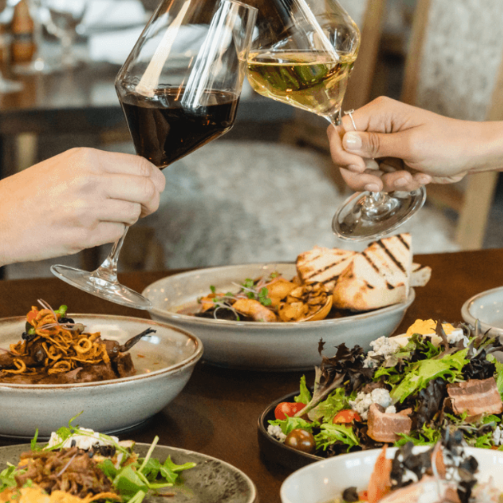 Assorted plates and two people holding wine glasses