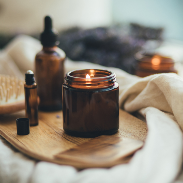 Close up of a lit candle and fragrances next to it